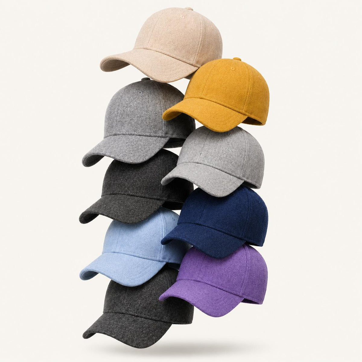 A stack of nine baseball caps in various colors, including beige, mustard yellow, light gray, charcoal, navy blue, light blue, and purple, arranged against a solid off-white background.