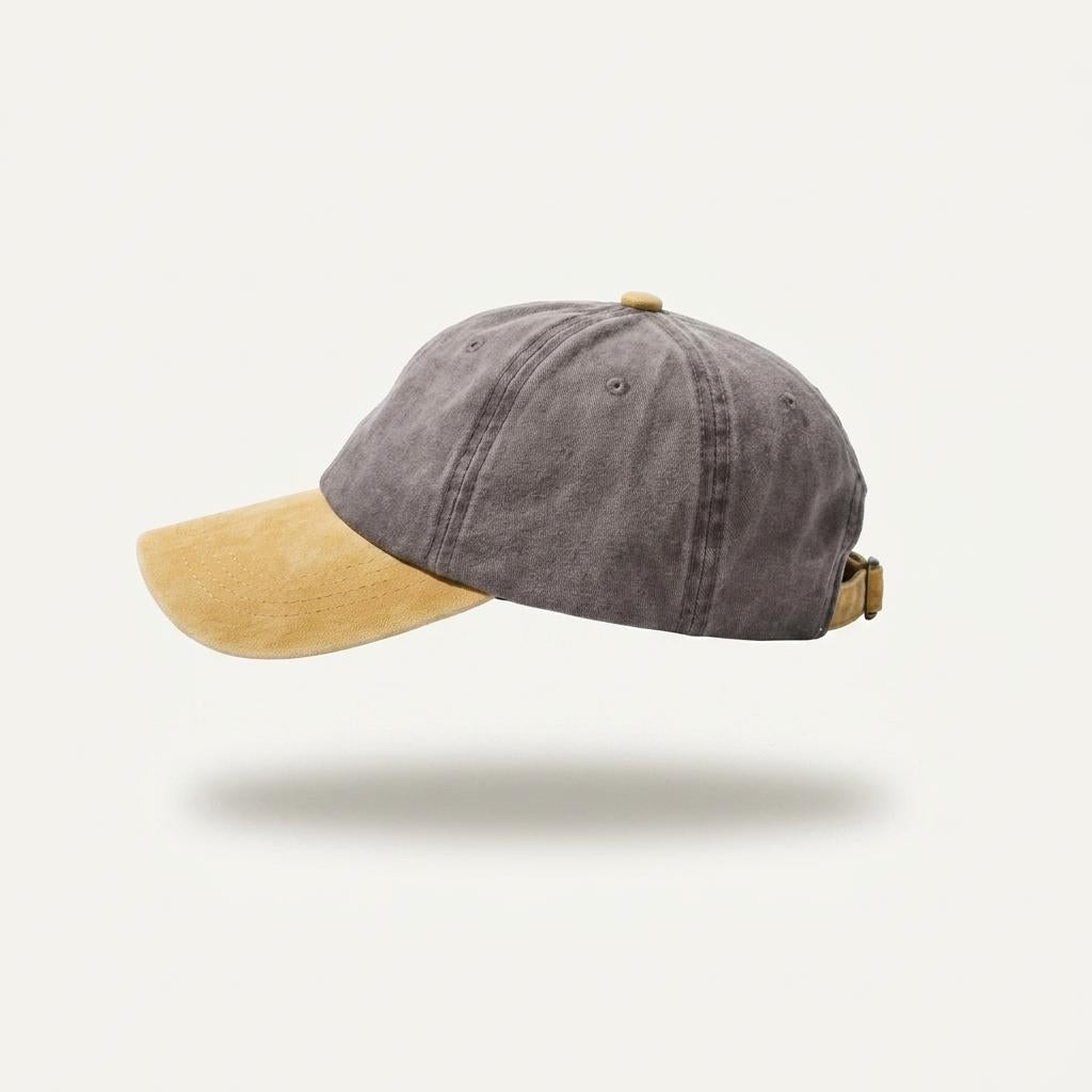 A washed dark gray baseball cap with a contrasting tan suede-look visor and matching tan buckle, shown against a light off-white background.