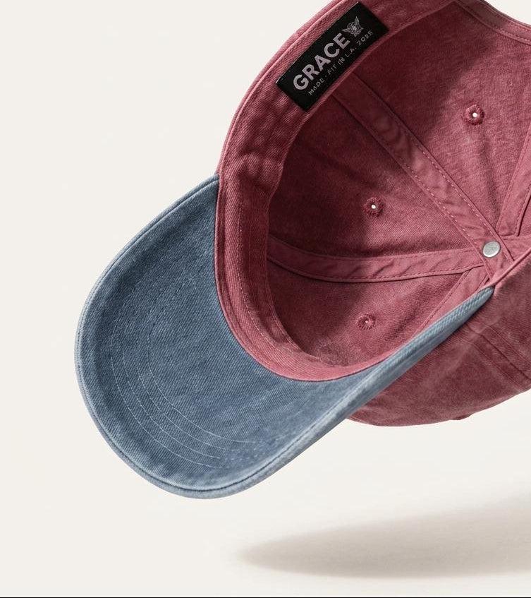 A dual-tone baseball cap with a dusty rose velvet crown and a blue denim-look curved brim, shown floating against a light beige background. The inside of the crown features a black brand label reading 'GRACE'.