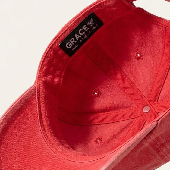 A red baseball cap shown floating at an angle, displaying the interior crown with a black brand label that reads 'GRACEY'.