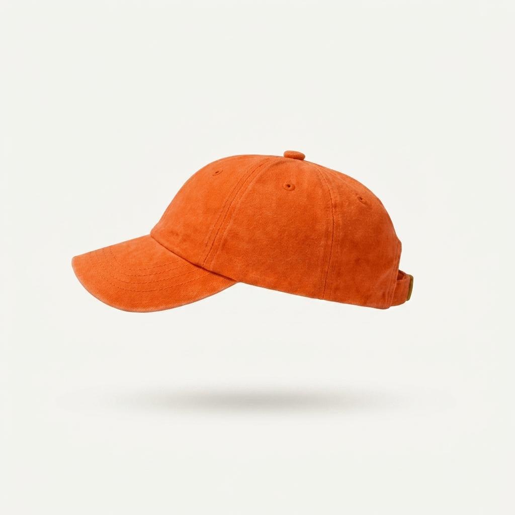 An orange washed cotton baseball cap shown from a side profile view against a clean, off-white background.