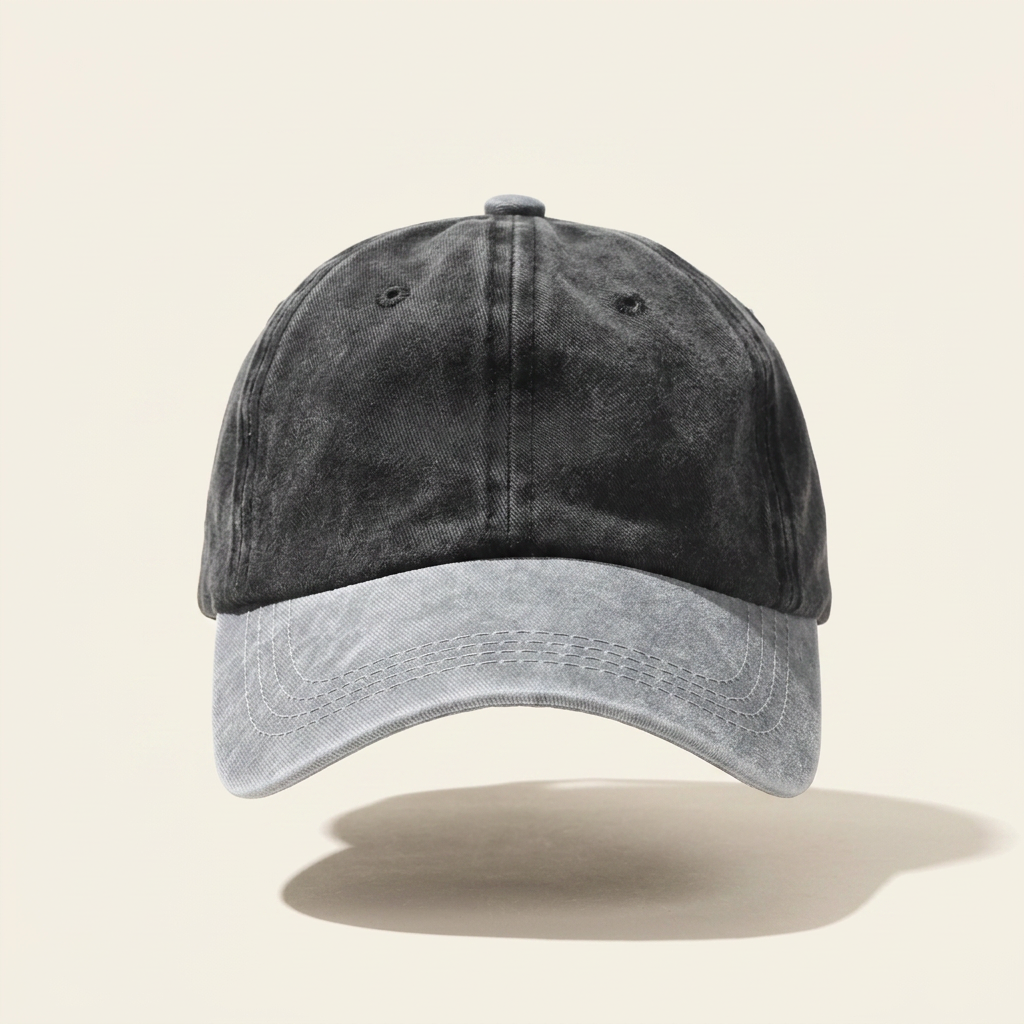 A washed black baseball cap with a light gray curved brim, shown against a solid beige background with a soft shadow underneath.
