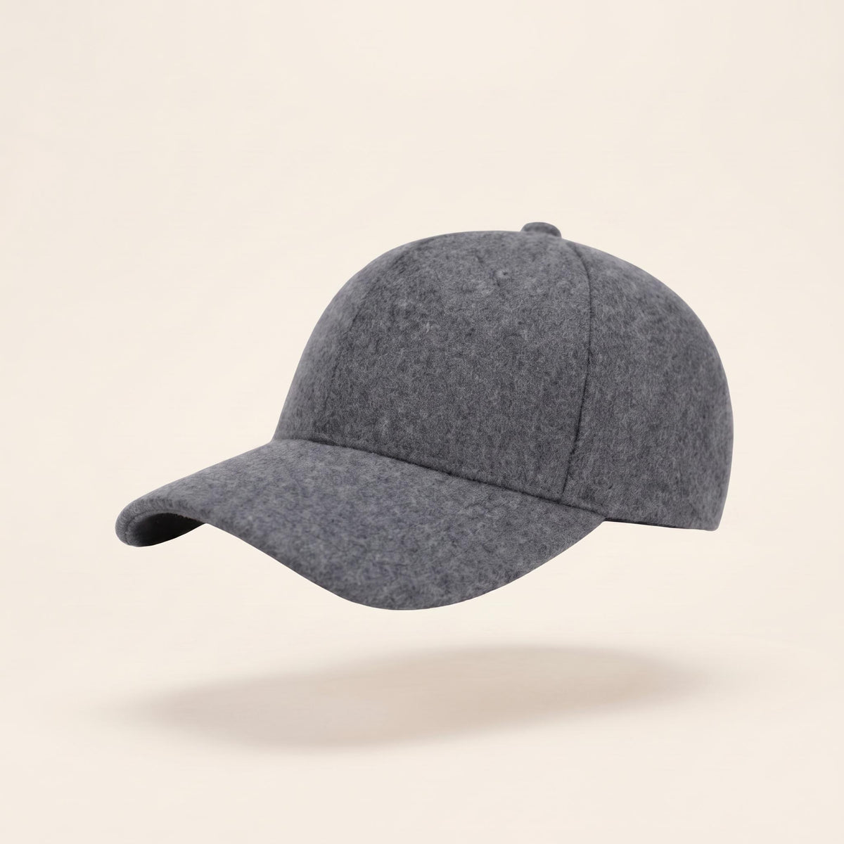 A dark gray felt baseball cap floating against a light beige background with a soft shadow underneath.