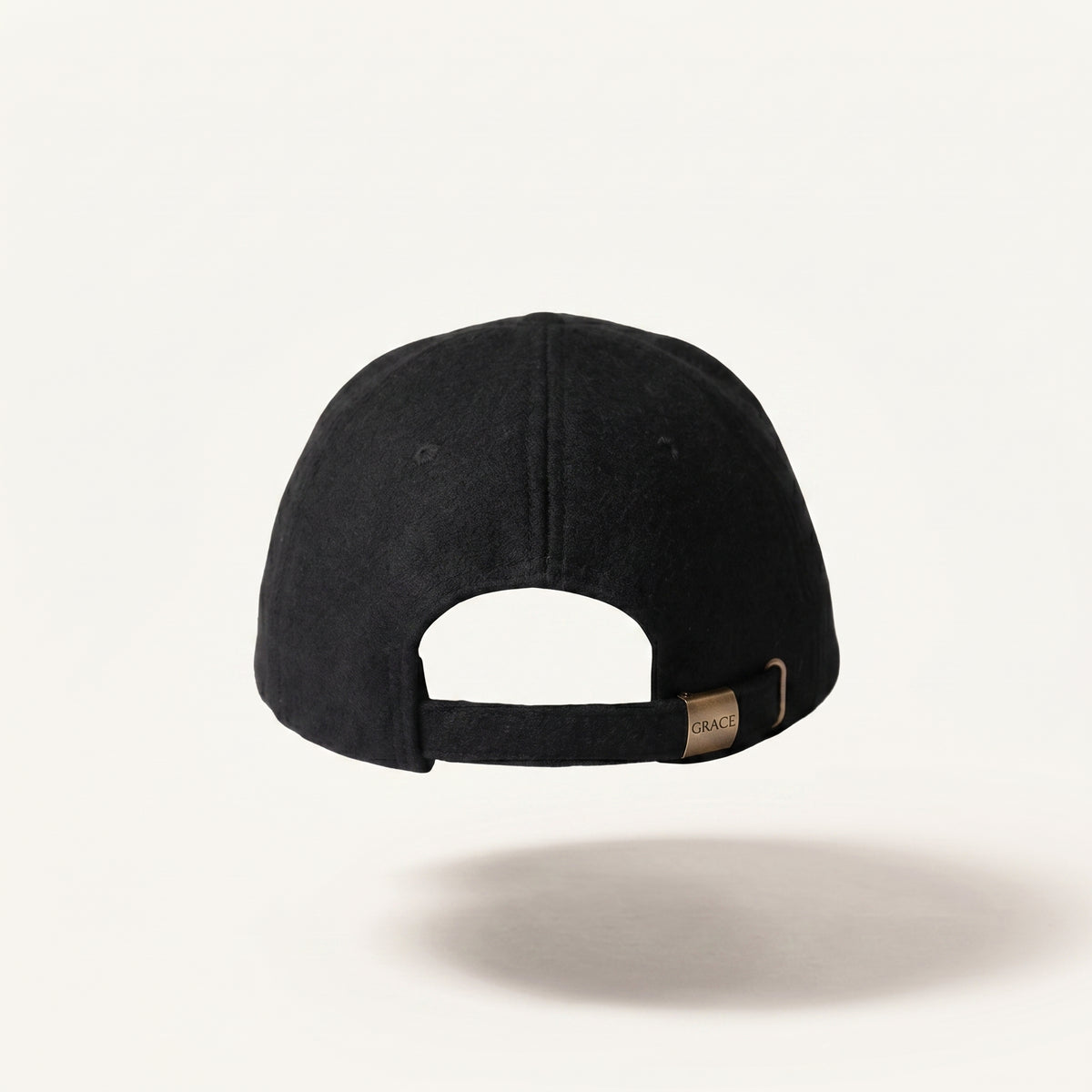A black baseball cap shown from the back, featuring a black adjustable strap with a small tan leather brand tag that reads 'C.A.