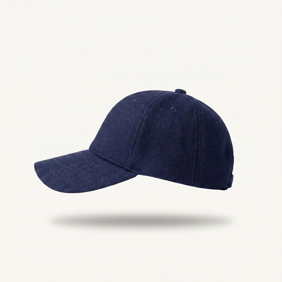 A navy blue baseball cap with a curved brim, shown floating against a light off-white background with a soft drop shadow underneath.