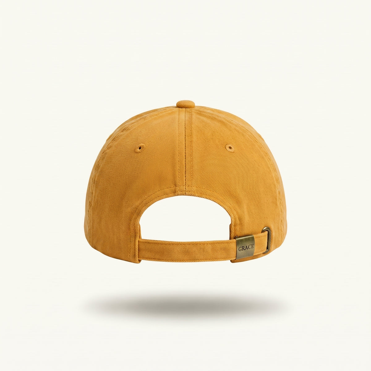 A mustard yellow baseball cap shown from the back, featuring a fabric strap with a small metallic brand tag that reads 'CRAZY'. The cap is centered against a clean, off-white background with a soft drop shadow underneath.