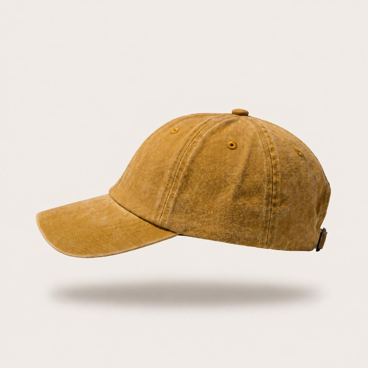 A washed mustard yellow baseball cap shown from a side profile against a light beige background.