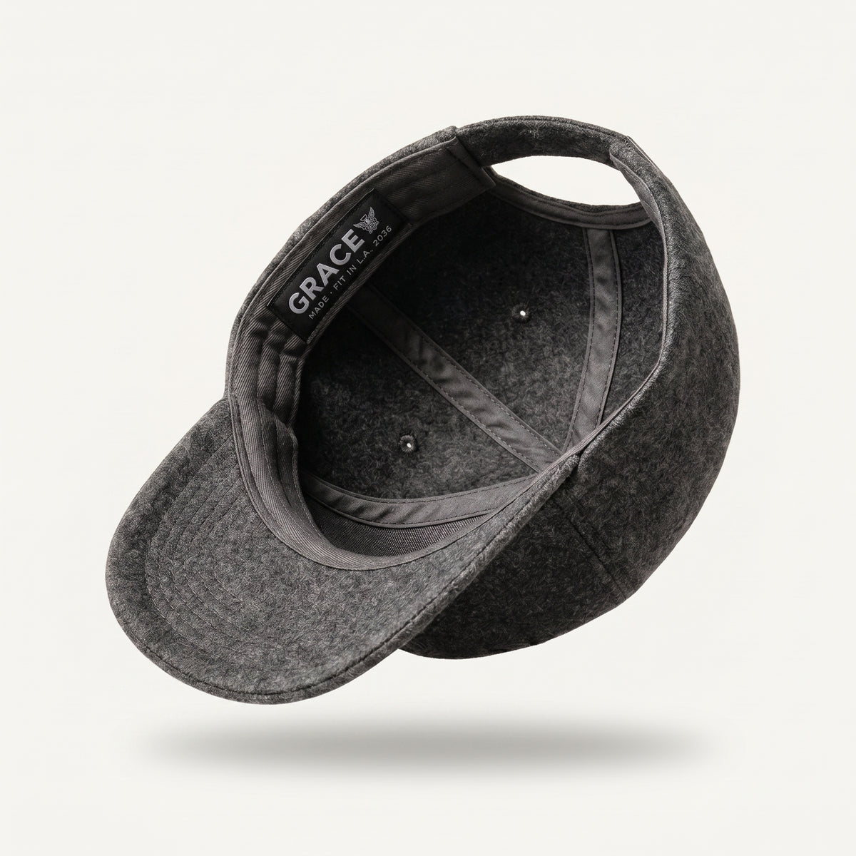 A dark gray felt baseball cap shown floating at an angle, displaying the interior with a black brand label that reads 'GRACE WILMINGTON'.