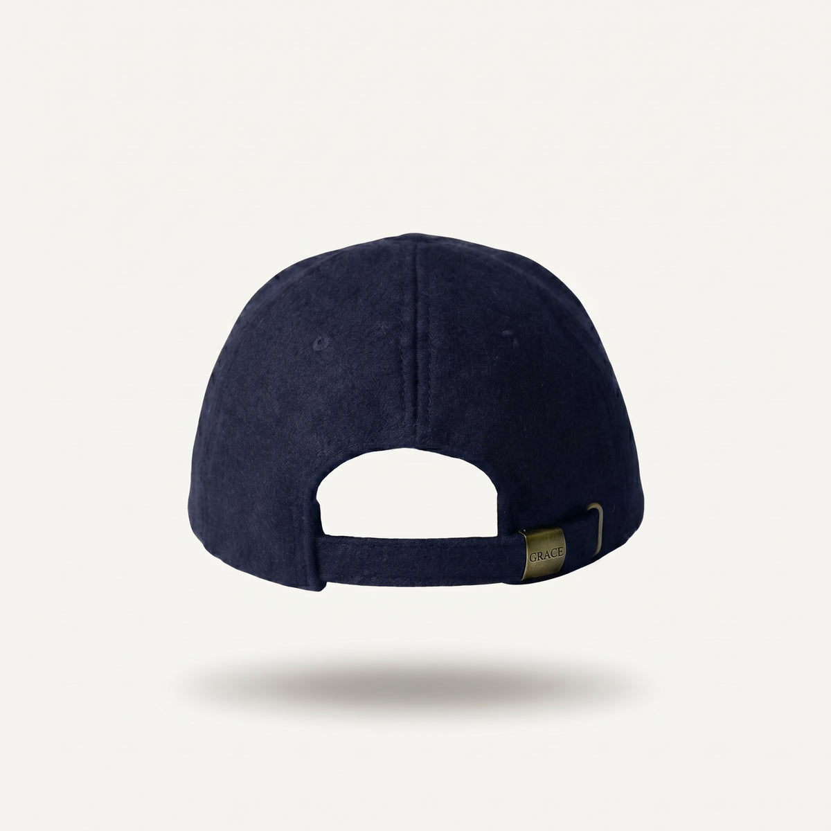 A navy blue baseball cap shown from the back, featuring a fabric texture and an adjustable strap with a small gold-toned metal tag, set against a clean off-white background.