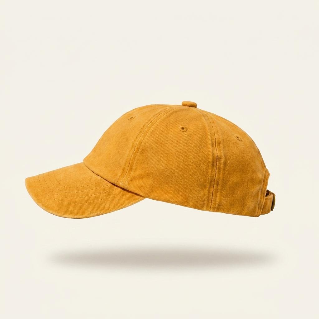 A washed mustard yellow baseball cap shown from a side profile view against a light cream background with a soft drop shadow.