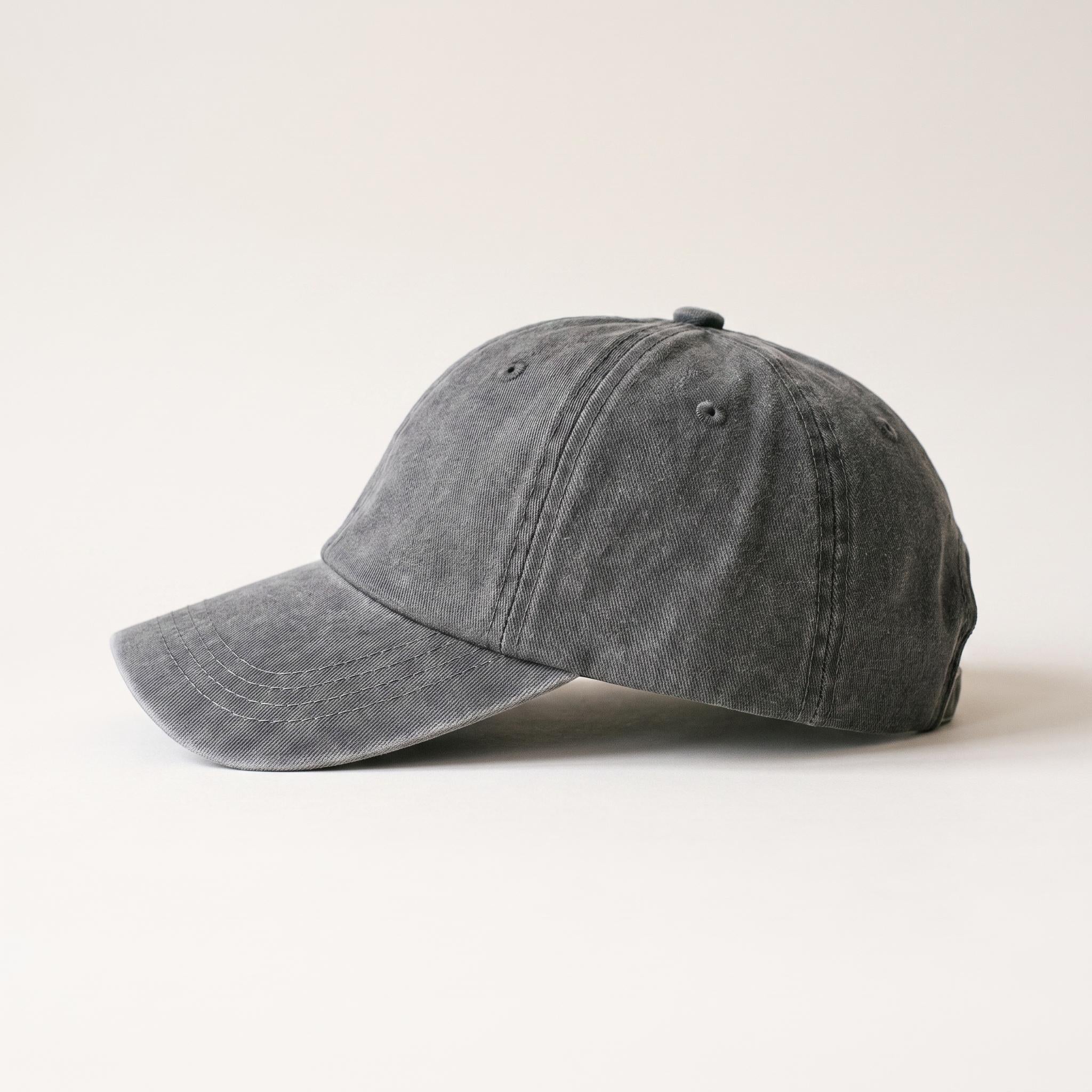 A washed dark gray baseball cap shown in profile against a clean, light off-white background.