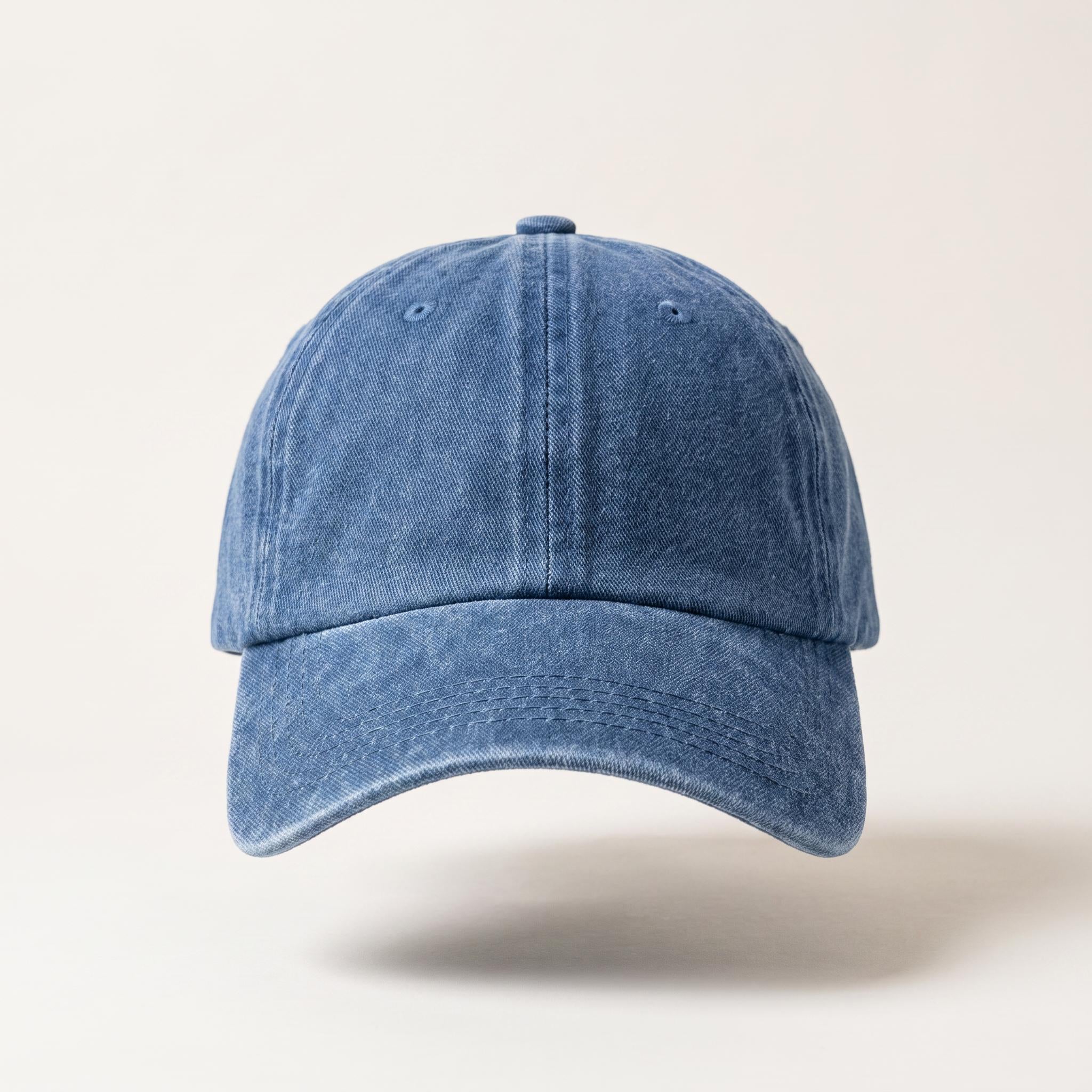 A classic six-panel baseball cap in a washed, distressed medium blue denim-like fabric, shown from a front-facing perspective against a light beige background.