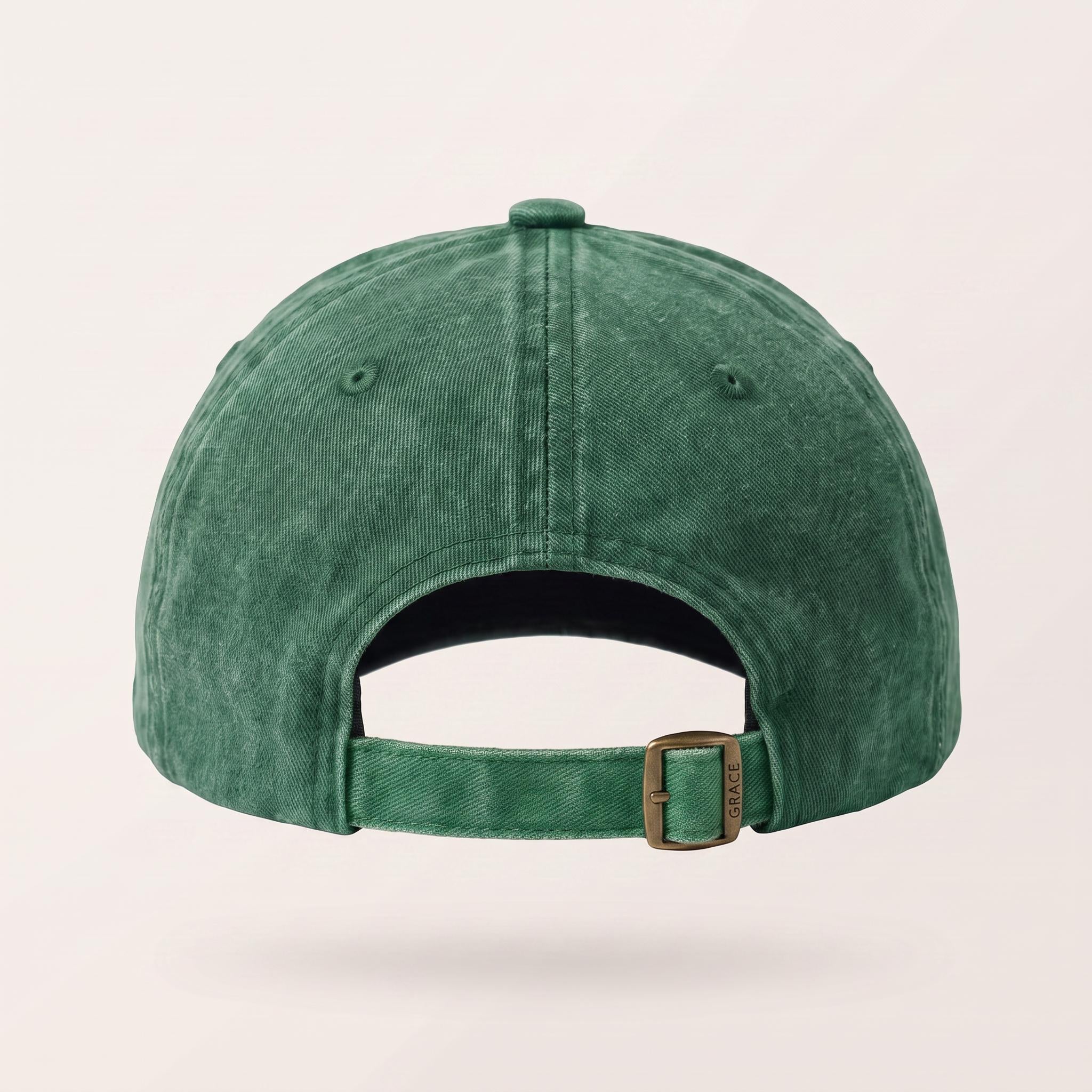 The back view of a washed green baseball cap with an adjustable strap and a bronze-colored metal buckle, shown on a light beige background.