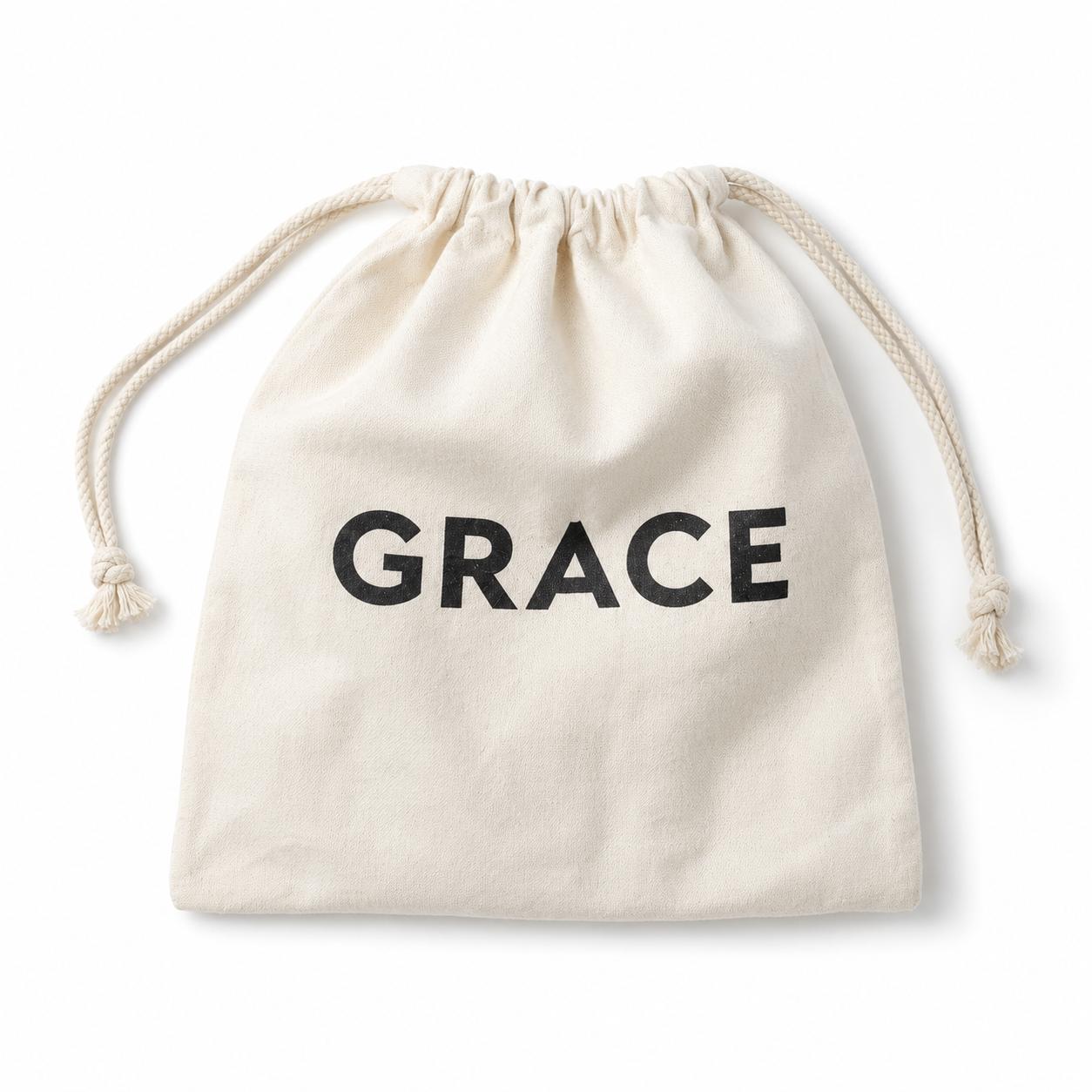 An off-white canvas drawstring pouch with the word 'GRACE' printed in bold black letters on the front, set against a plain white background.