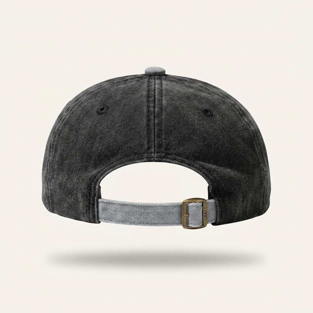 A dark gray acid-wash baseball cap shown from the back, featuring a gray adjustable strap with a gold-tone metal buckle, set against a light beige background.