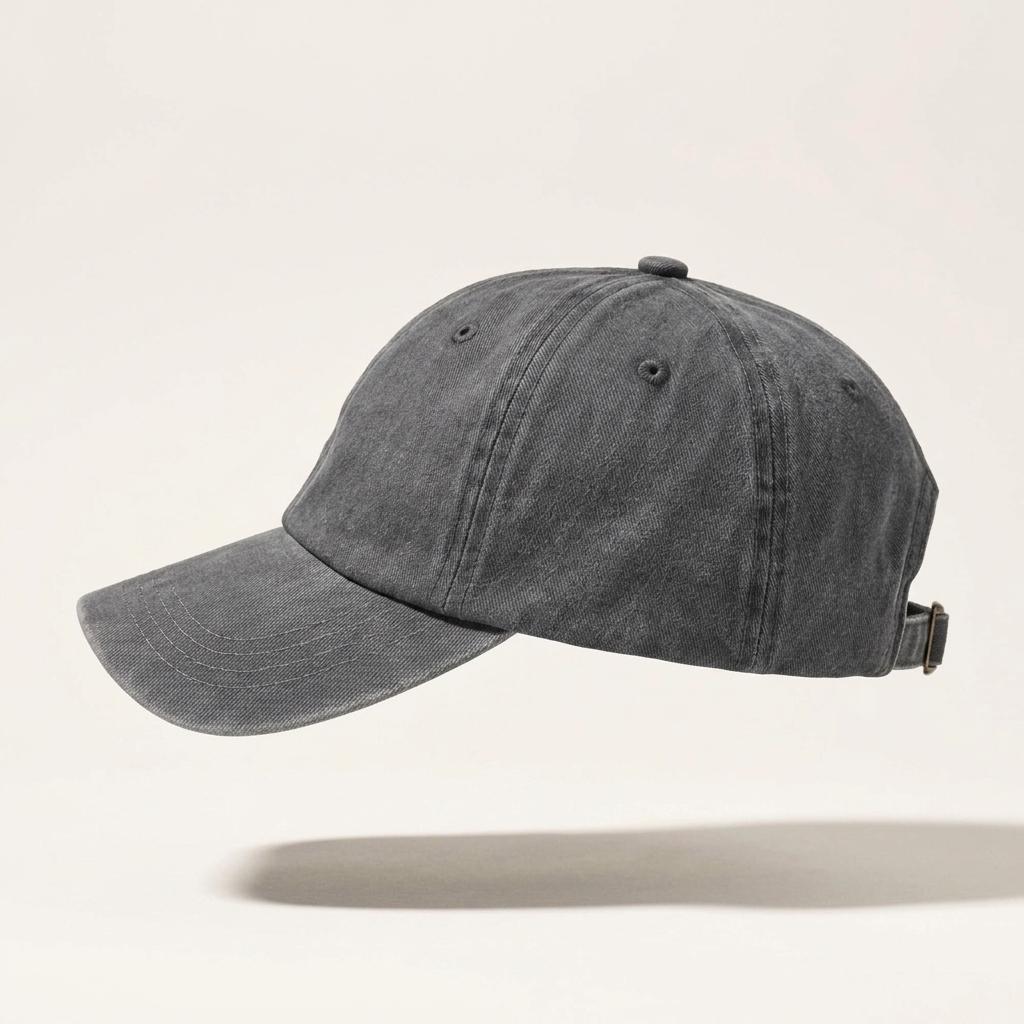 A dark gray washed cotton baseball cap with a curved brim and an adjustable back strap, shown floating against a light beige background with a soft shadow below.