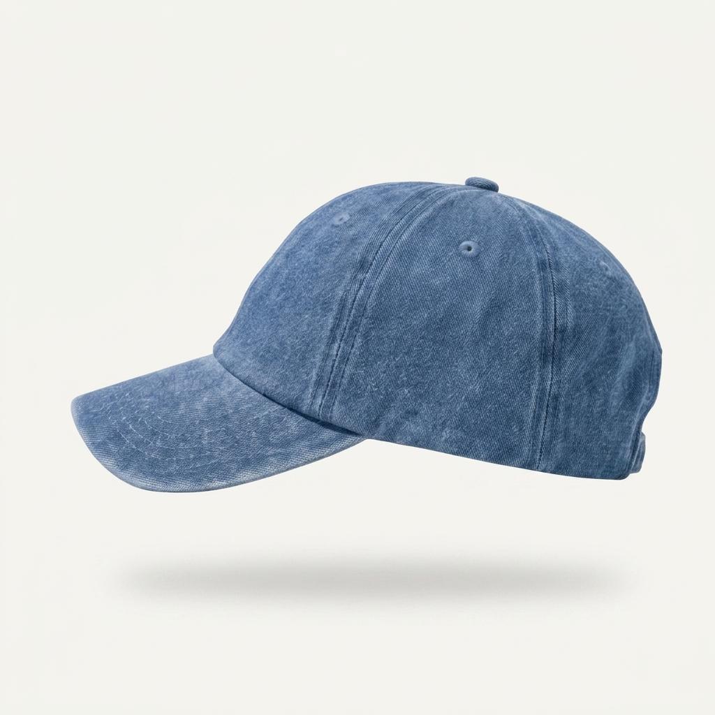 A washed blue denim baseball cap shown from a side profile view against a light off-white background with a soft drop shadow.