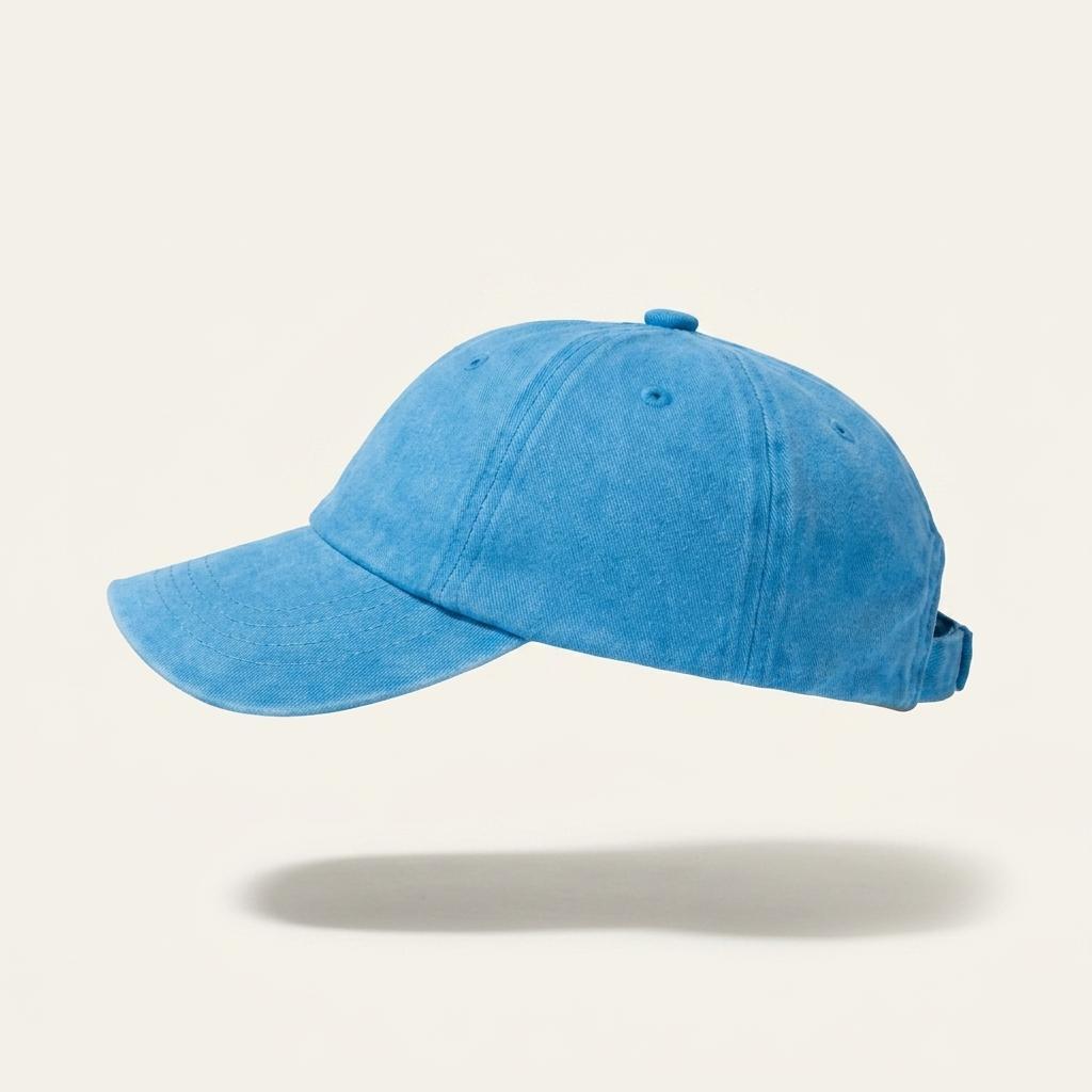 A light blue washed cotton baseball cap shown from a side profile against a warm off-white background with a soft shadow underneath.