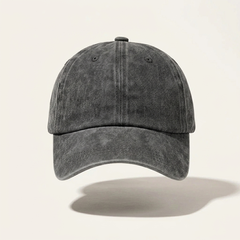 A dark gray washed cotton baseball cap with a curved brim, shown from a front-facing perspective against a light beige background with a soft shadow underneath.