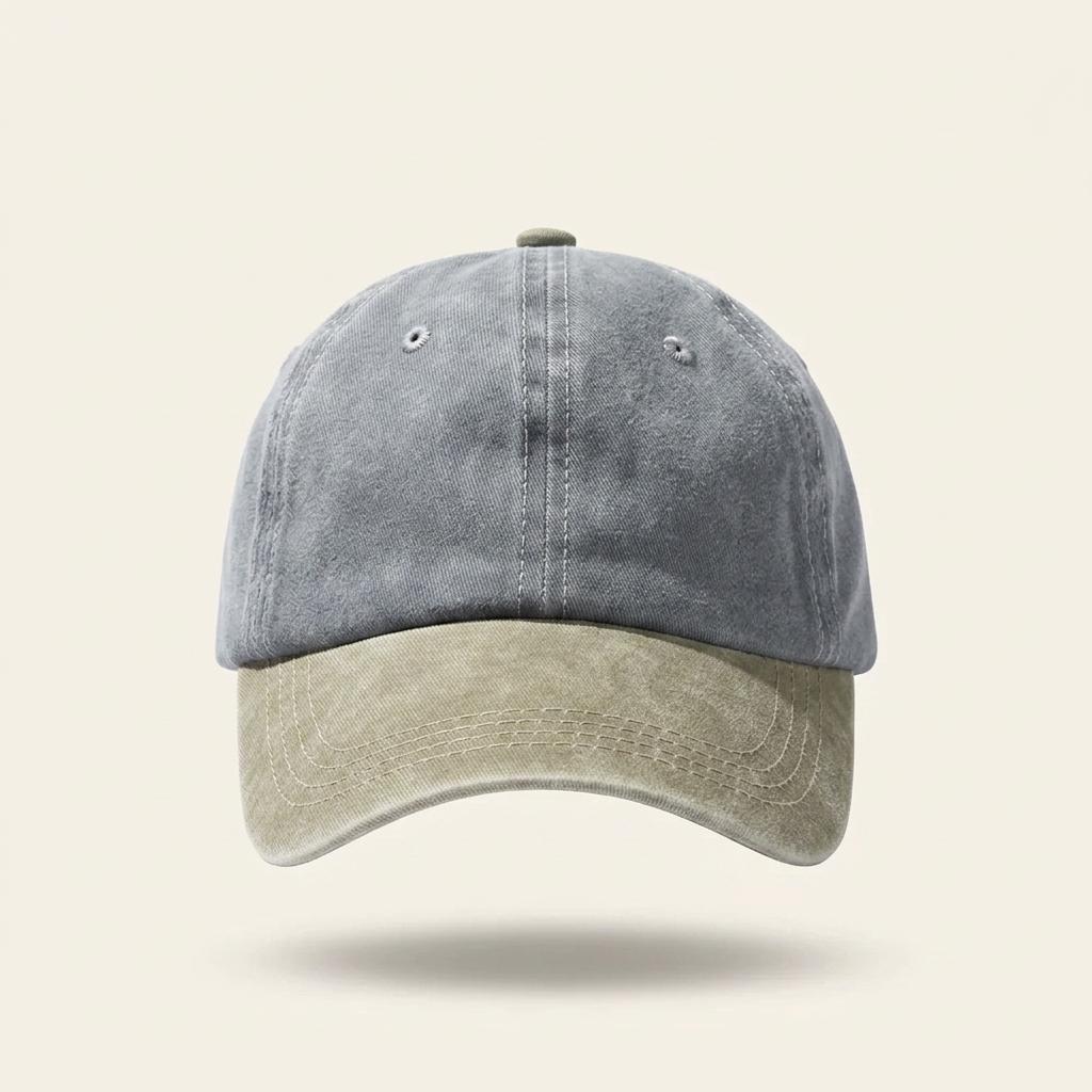 A washed dad hat baseball cap with a slate blue crown and a light beige brim, shown against a solid light beige background.