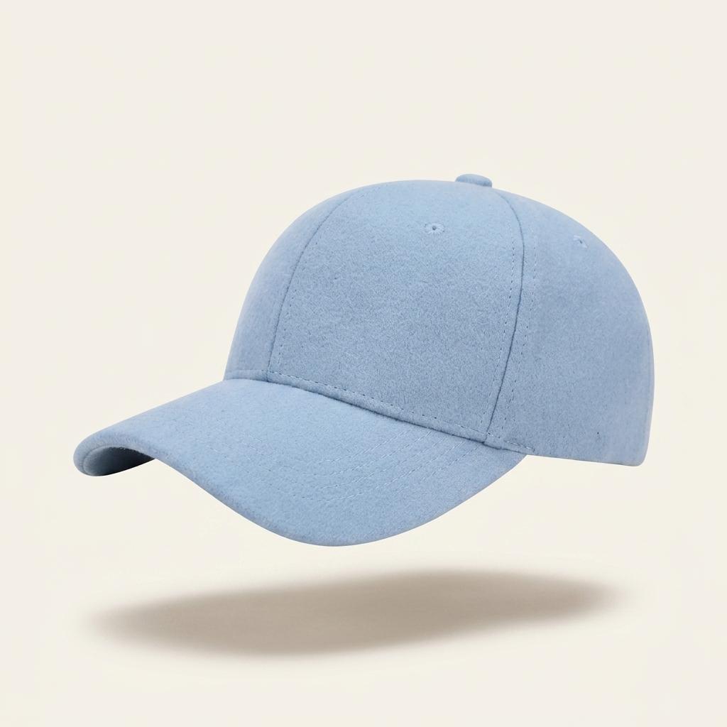 A light blue baseball cap floating against a solid cream-colored background with a soft shadow underneath.