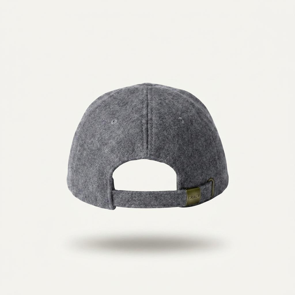 The back view of a dark gray felt baseball cap with an adjustable strap and a small brass-tone brand tag, shown on a light off-white background.