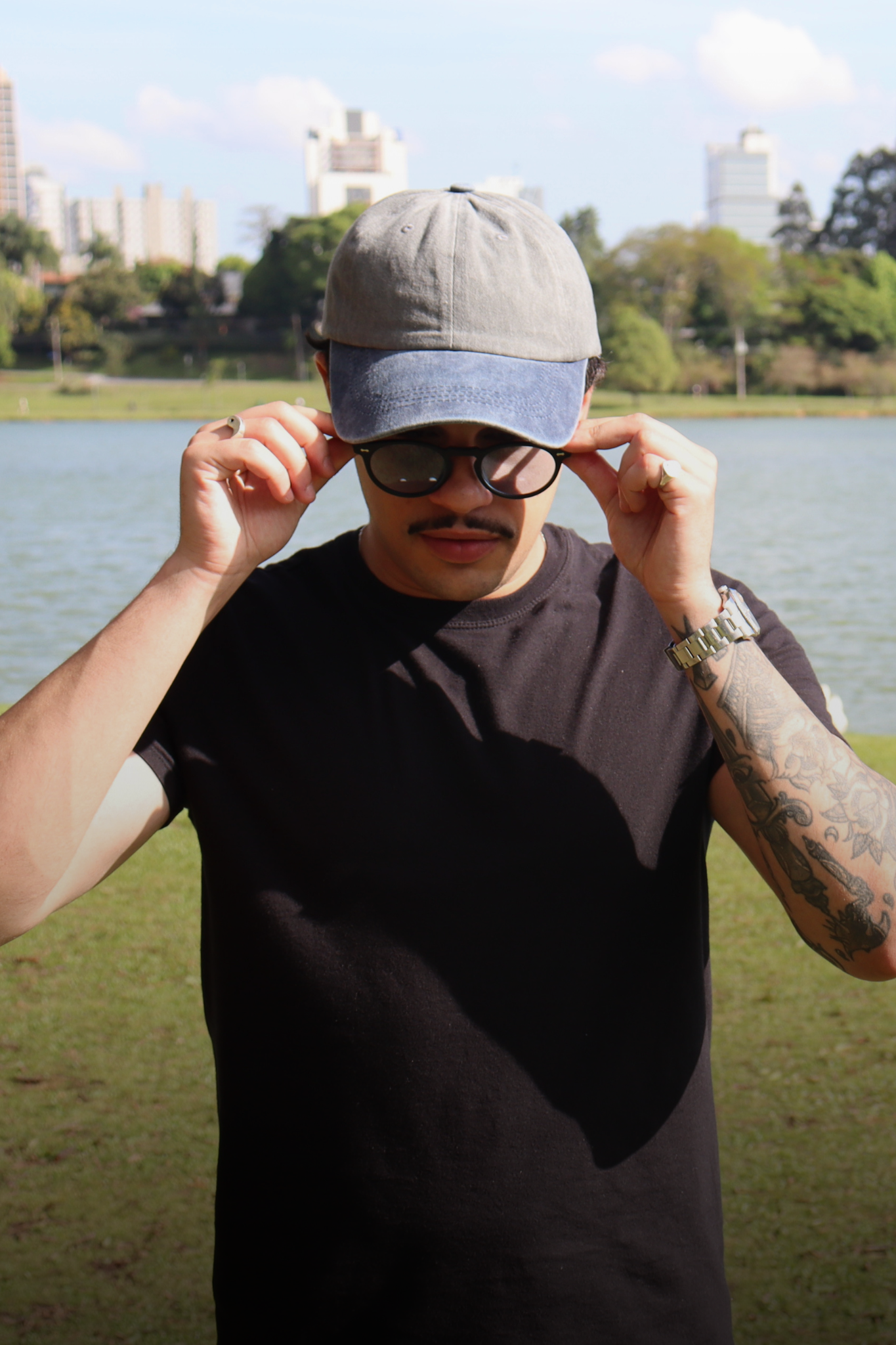 Person wearing a gray cap and sunglasses with a lake and trees in the background