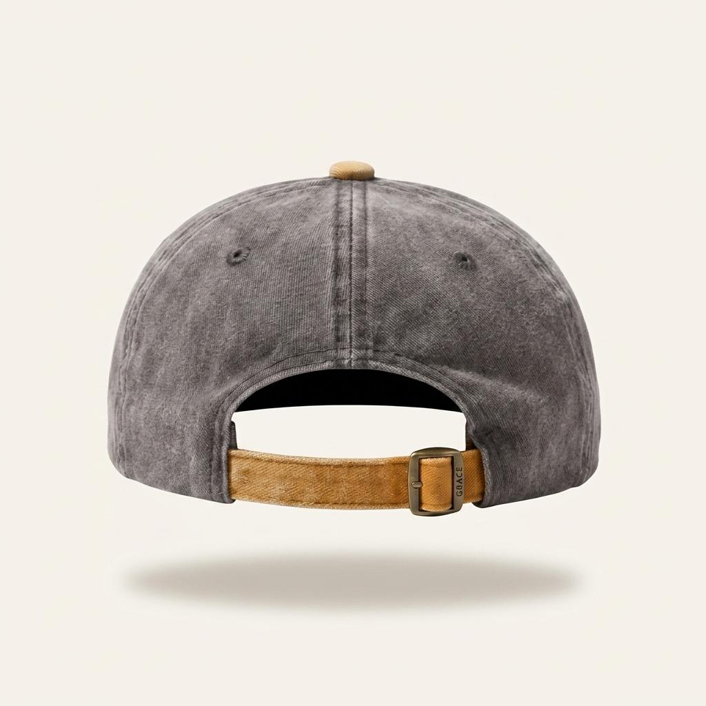 Rear view of a washed charcoal gray baseball cap with a tan adjustable fabric strap and metal buckle, shown on a light beige background.